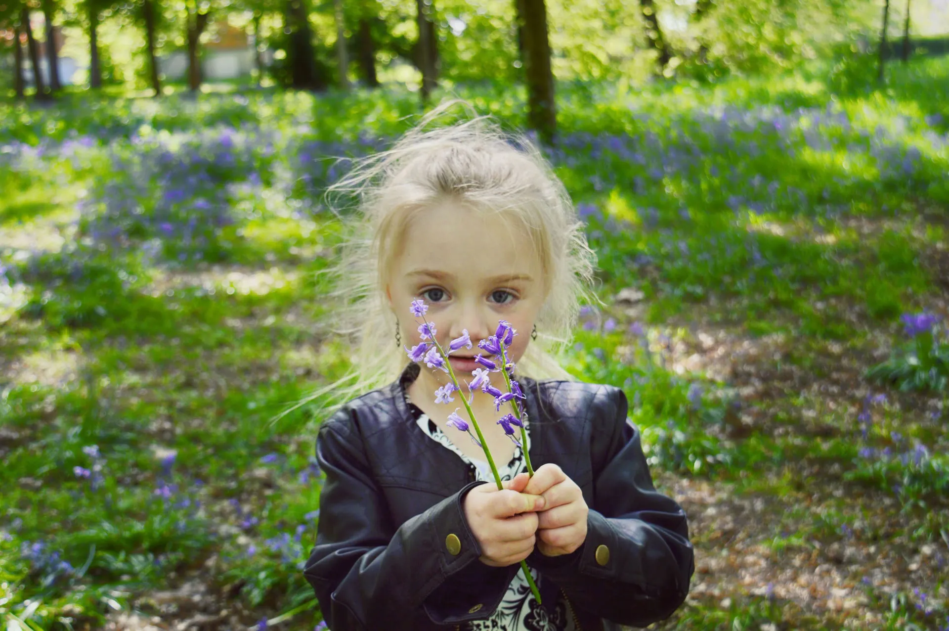 Portrait d'une petite fille qui nous montre ses fleurs à la main, dans un parc de Rouen
